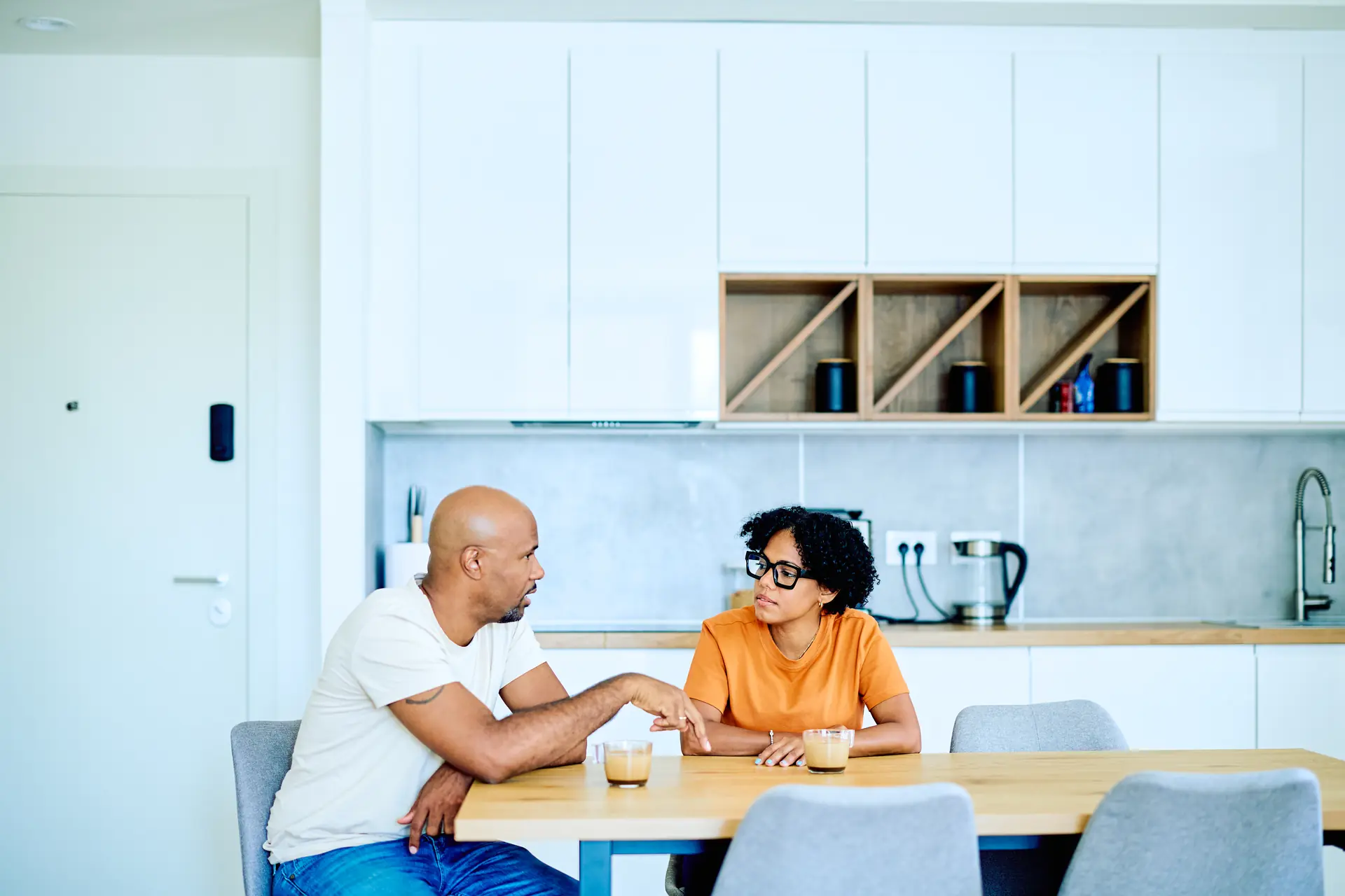 Couple talking at a kitchen table A couple sitting at a kitchen table at home having a calm and serious conversation