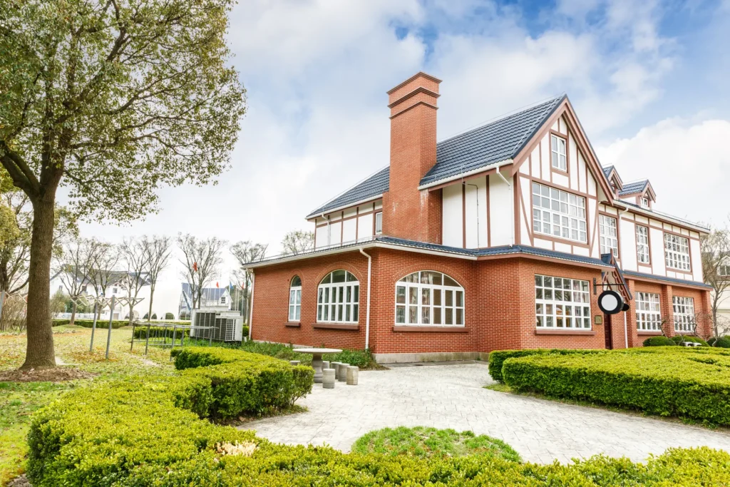 A red brick family home with a mature garden on a bright day
