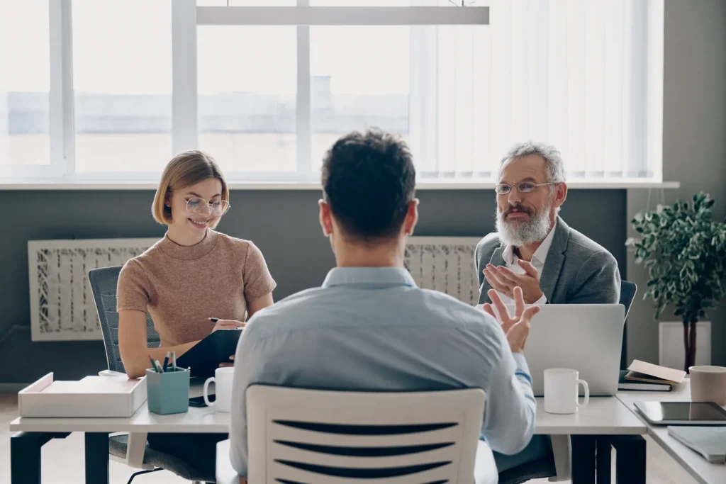 Three people sitting around a table in a calm meeting room during a mediation session