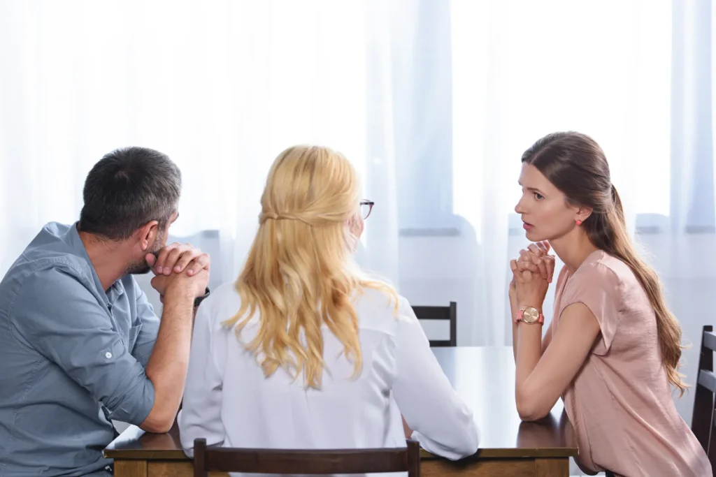 Three people talking calmly around a table in a bright room