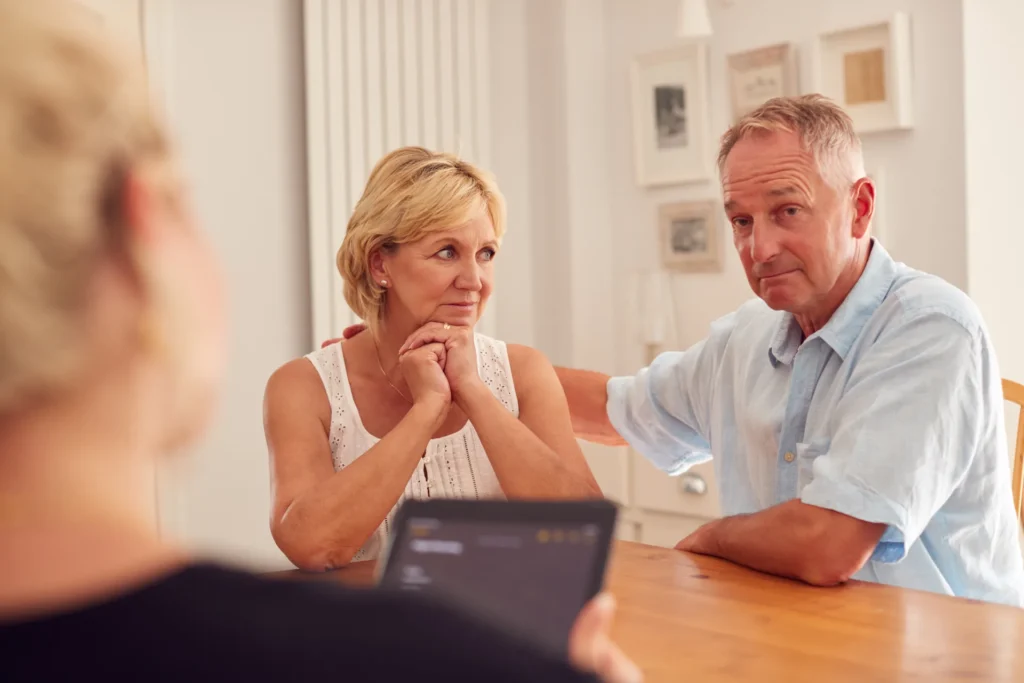 A mature couple at a table talking through their financial options with a mediator