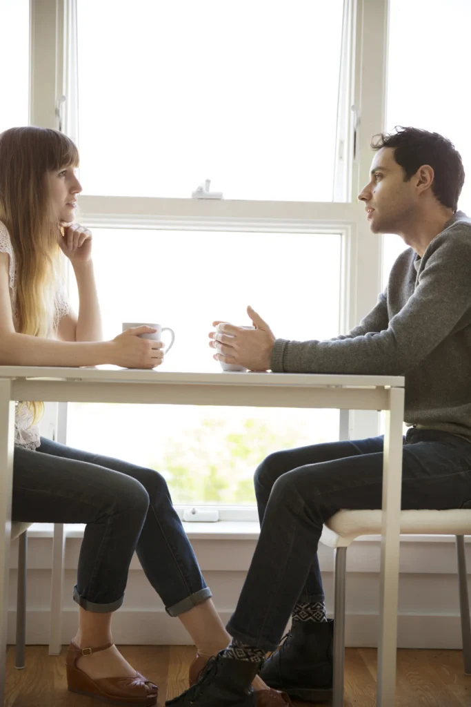 Two people sitting across a table by a window having a calm conversation about separation